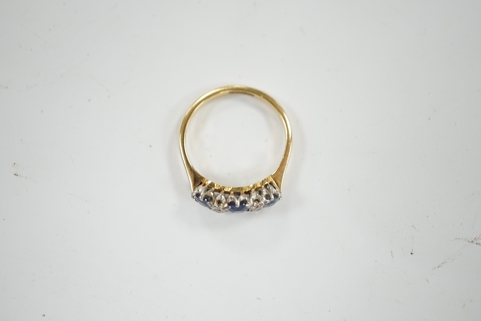 An 18ct and plat. three stone sapphire and four stone diamond chip spacer set ring, size N/O, gross weight 3.2 grams. Condition - poor to fair